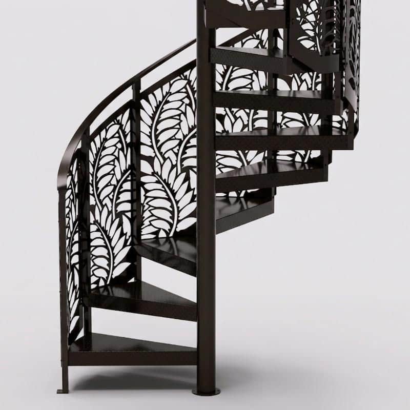 A dark metal spiral staircase with decorative railings featuring an intricate leaf pattern, set against a plain light background.